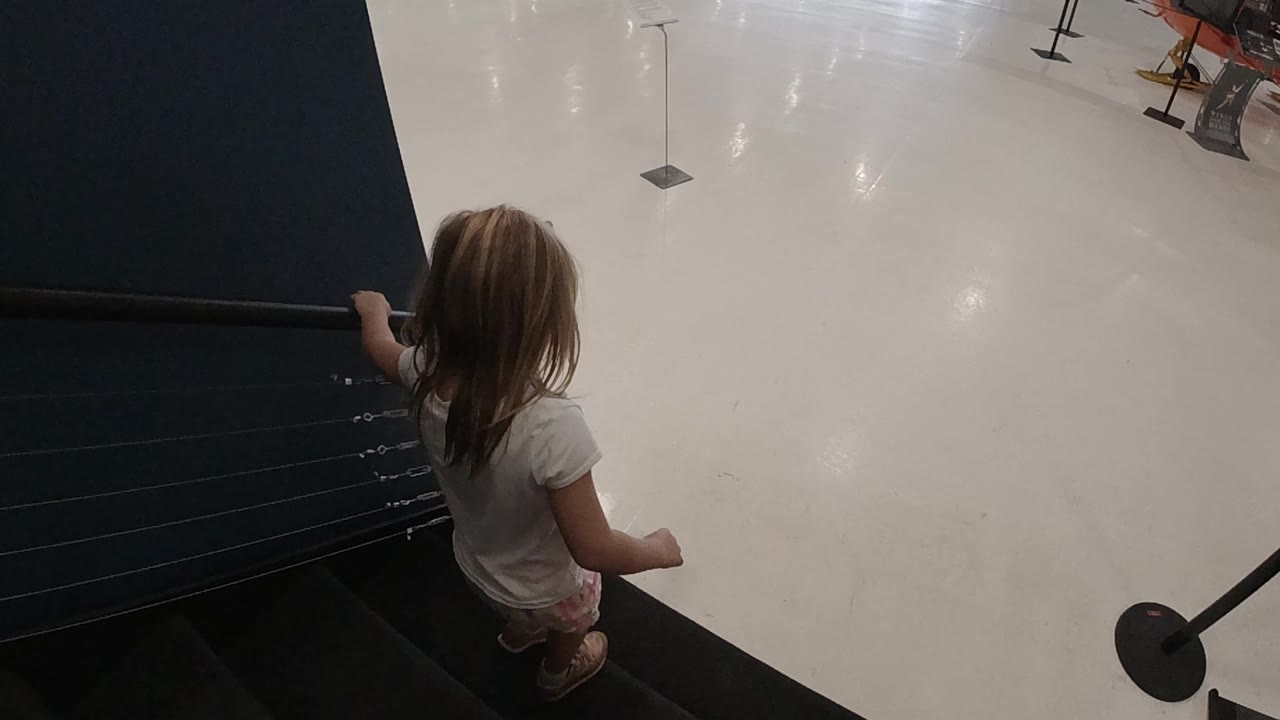 Young girl holds the stair rail while descending.