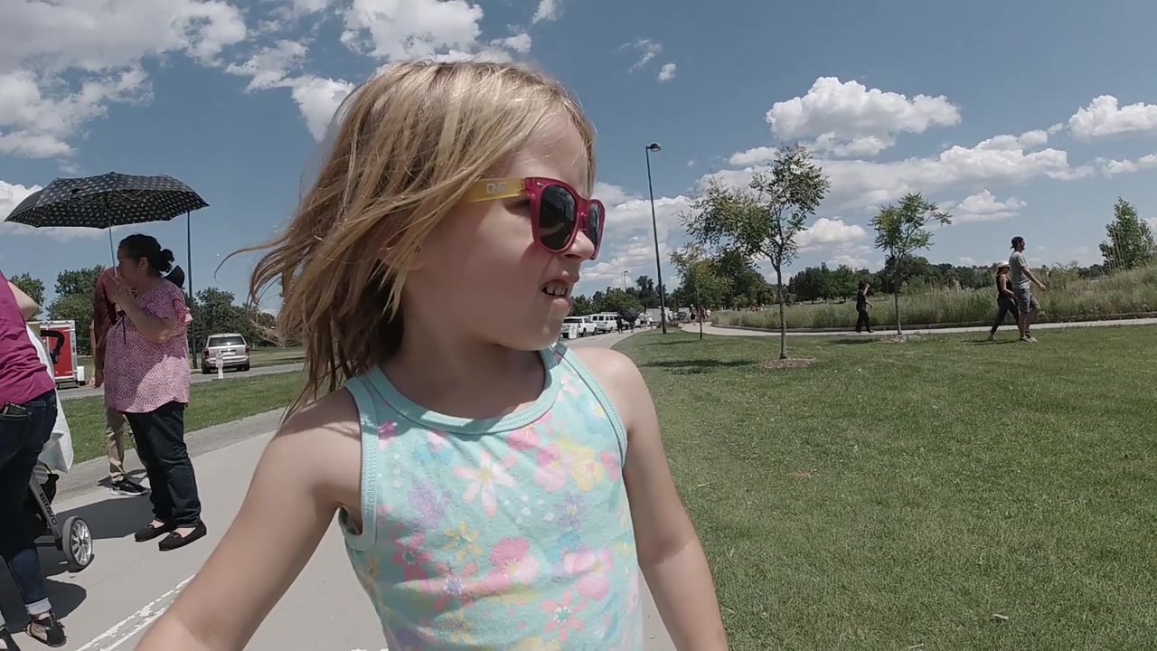 Child in sunglasses beside sidewalk and lawn