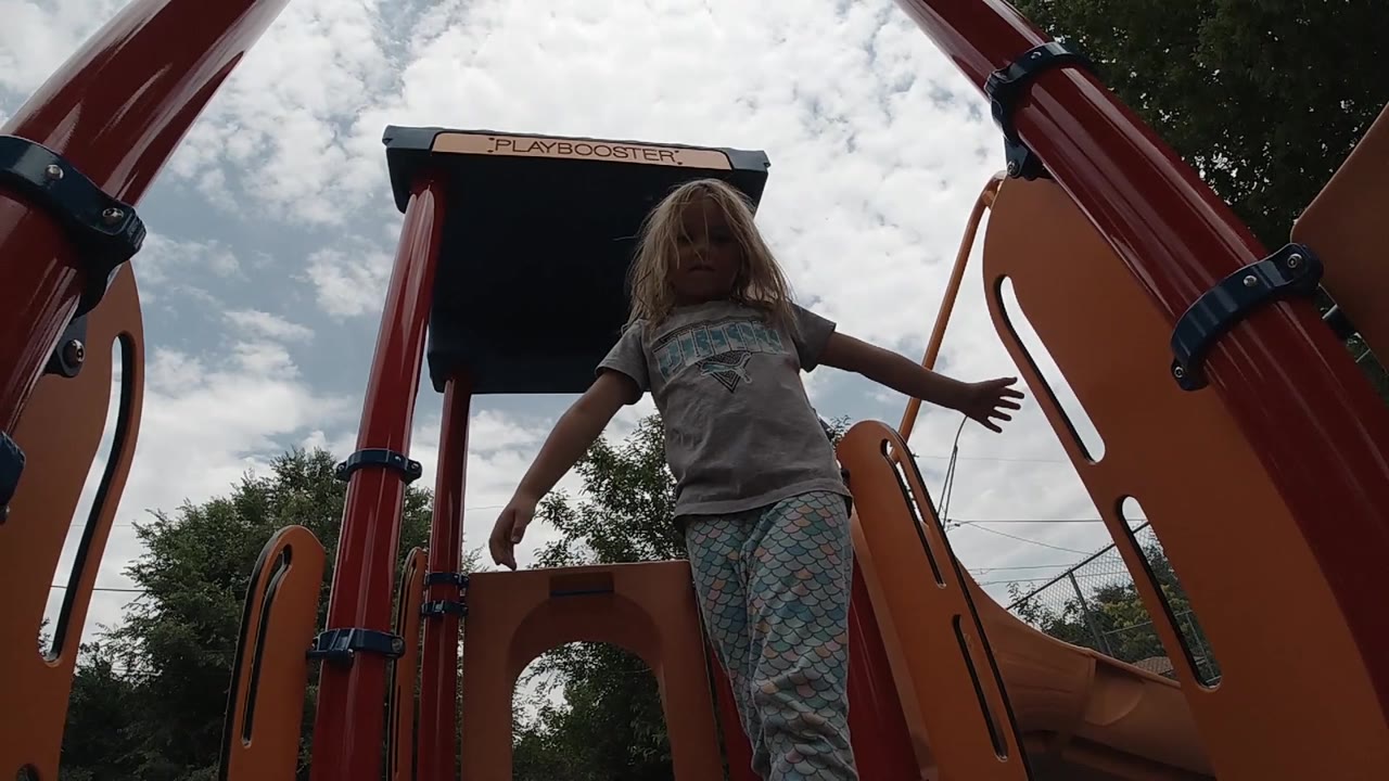 Girl lowering her arms on playground equipment.