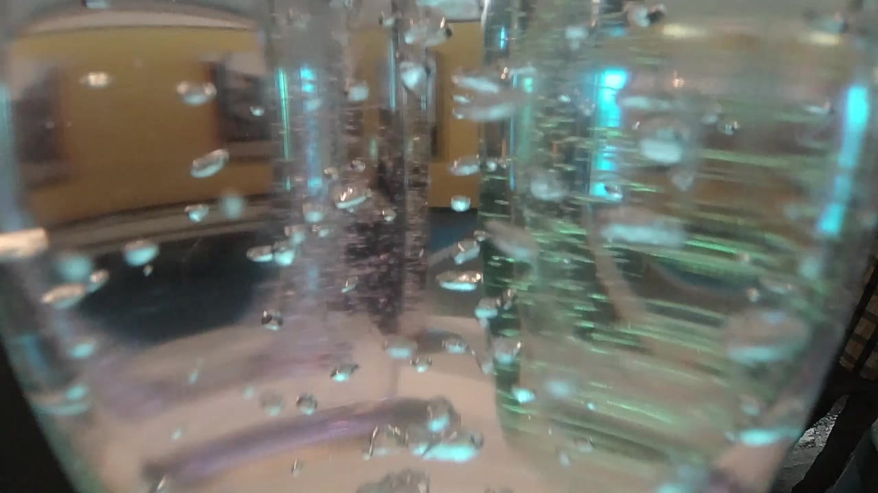Opening close-up of air bubbles suspended near rippled glass and teal reflections in Denver collection footage, with no visible people.