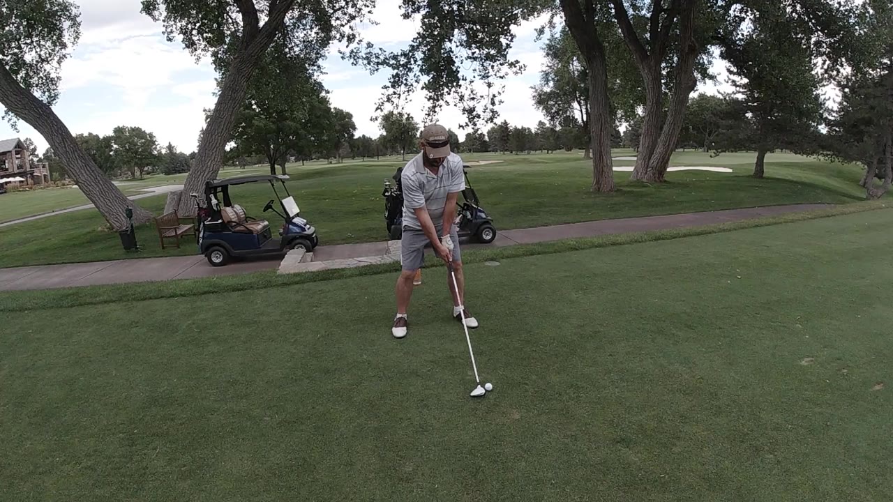 Man preparing to hit a golf ball on a course.