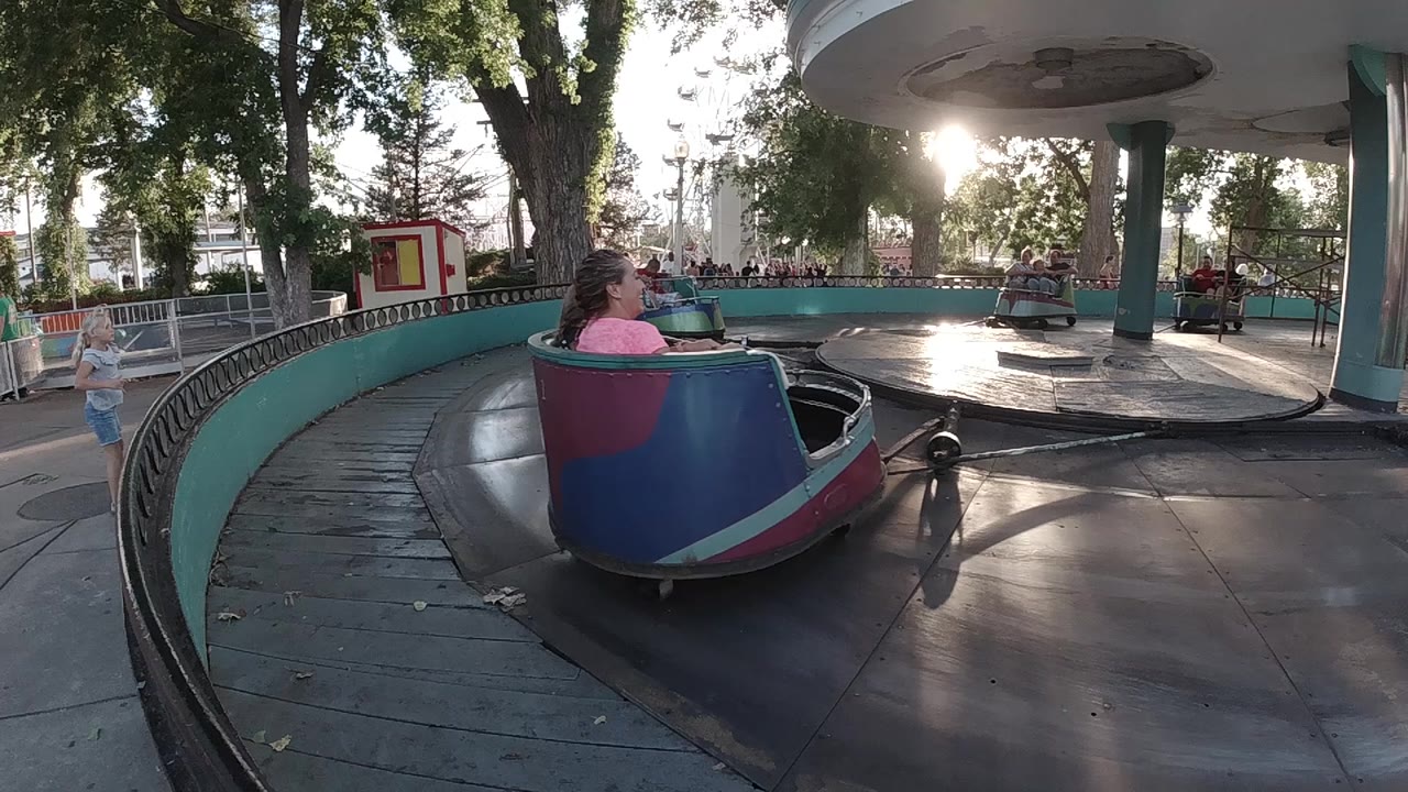 Colorful cup car moving along the circular ride platform