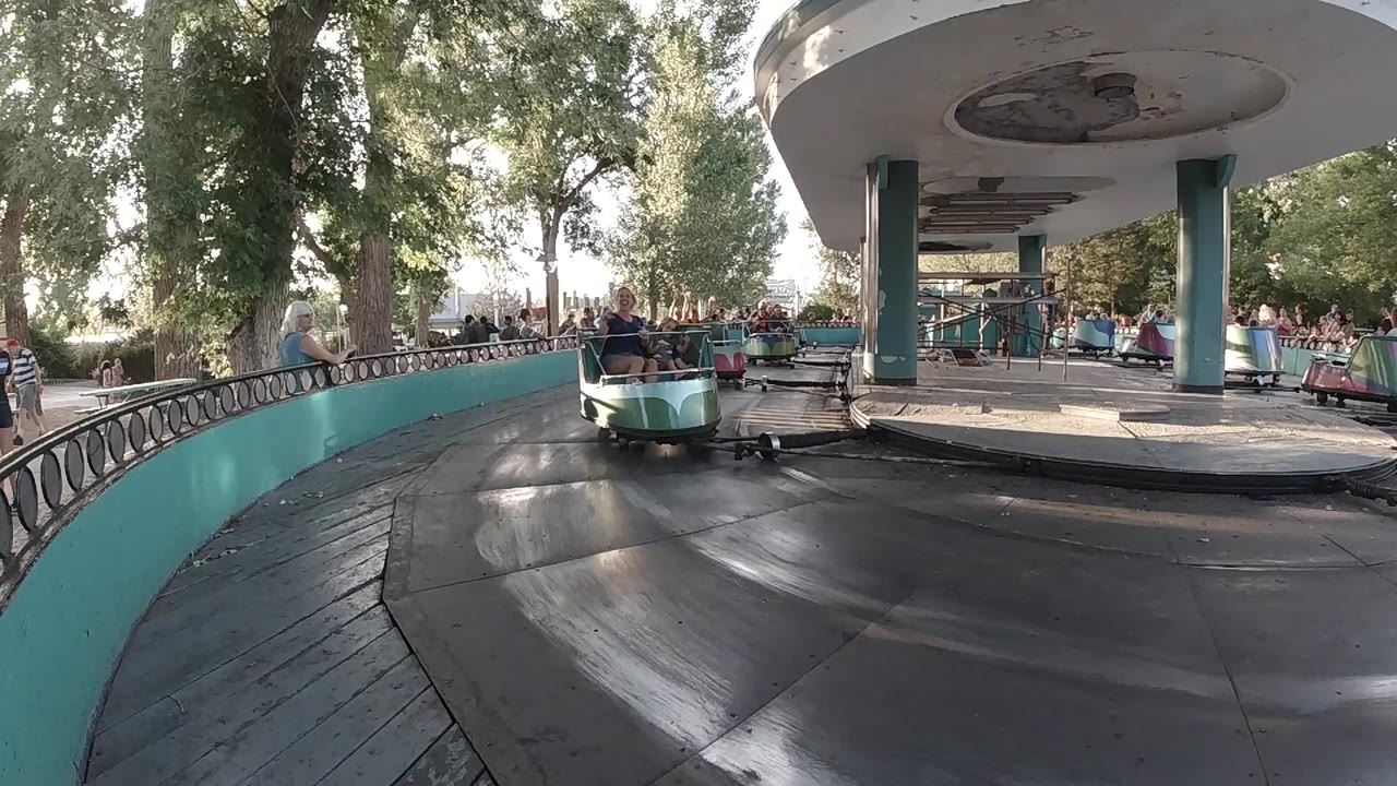 Colorful carousel car approaching on an outdoor track.
