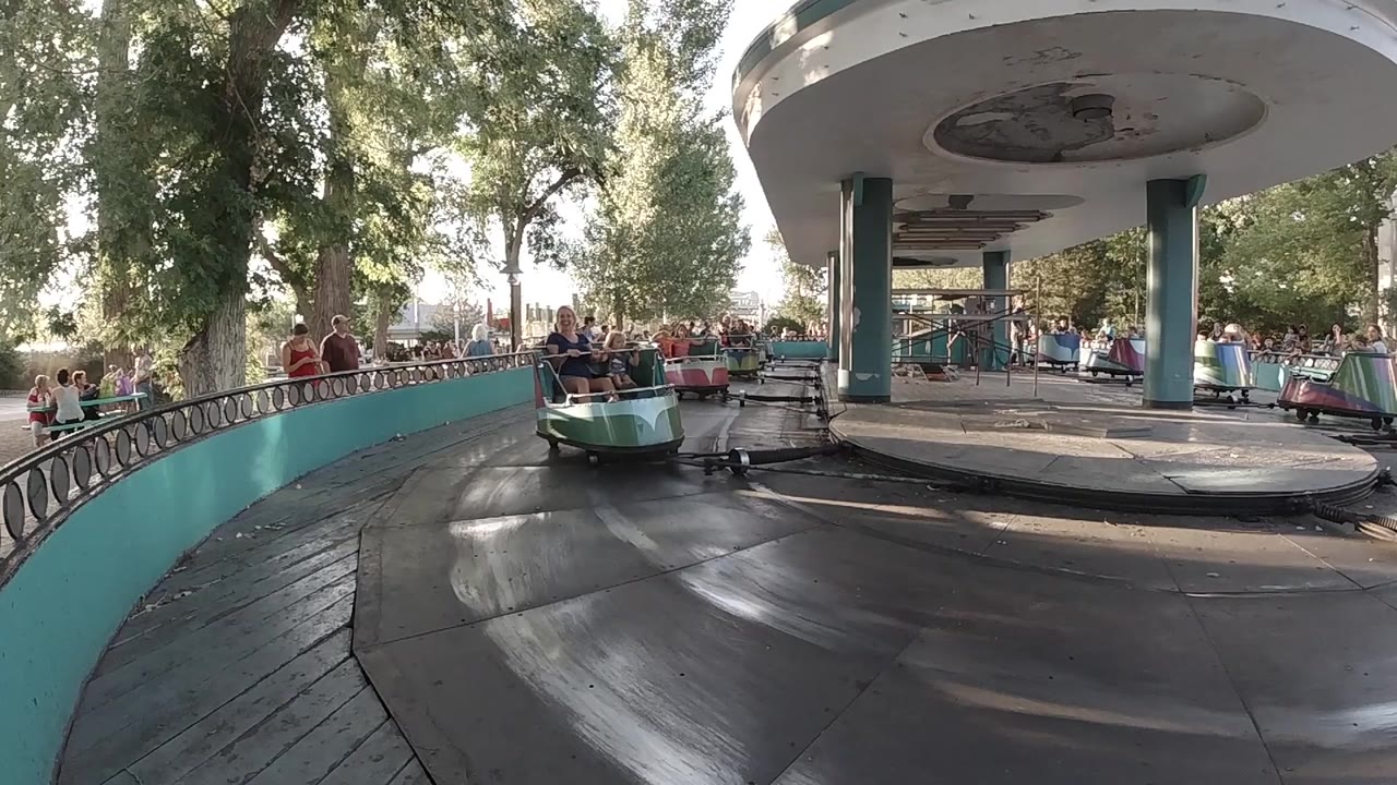 Cup ride car nearing the camera beside teal railings