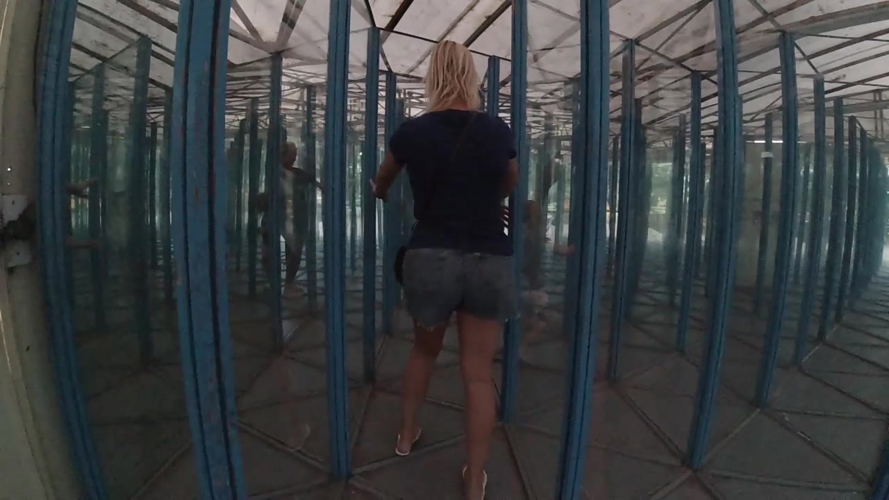 The following view keeps the blonde woman near center while reflections duplicate the glass doorway lines around her.