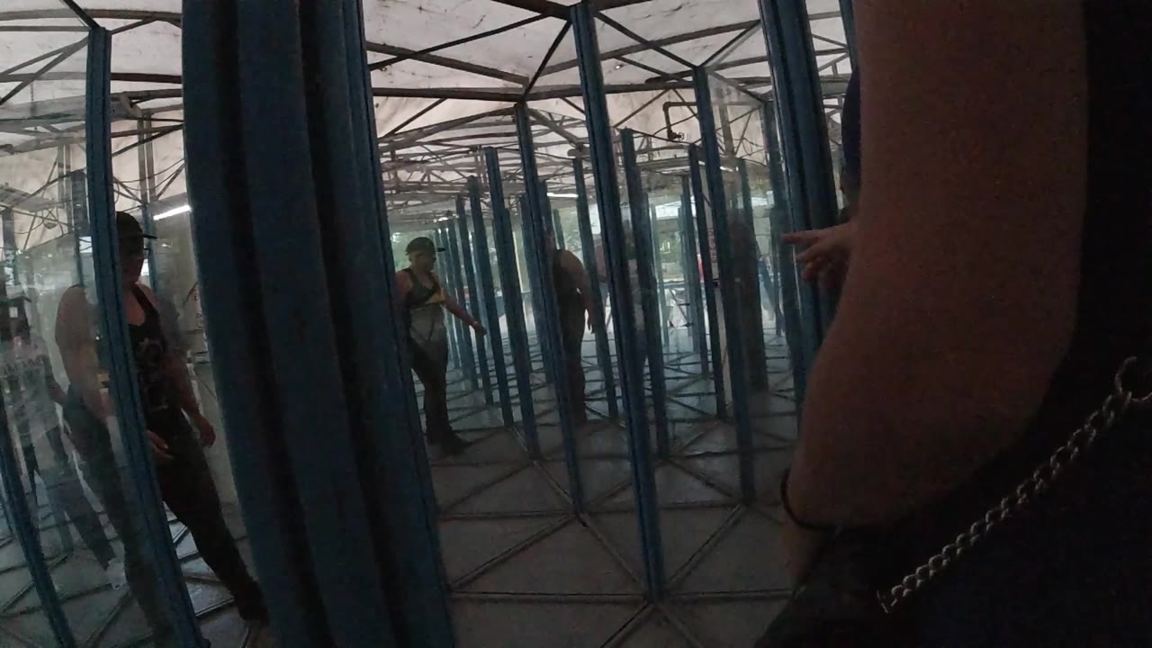 At 0:00 in Colorado, an adult in dark clothing stands close to the camera while blue-framed glass panels repeat into the background.