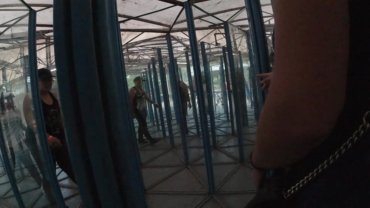 Close adult arm and distant person in reflective glass structure.