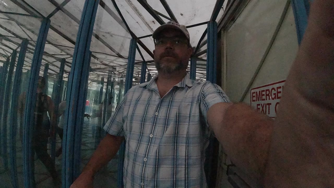 Bearded man in glasses walking through a glass corridor.