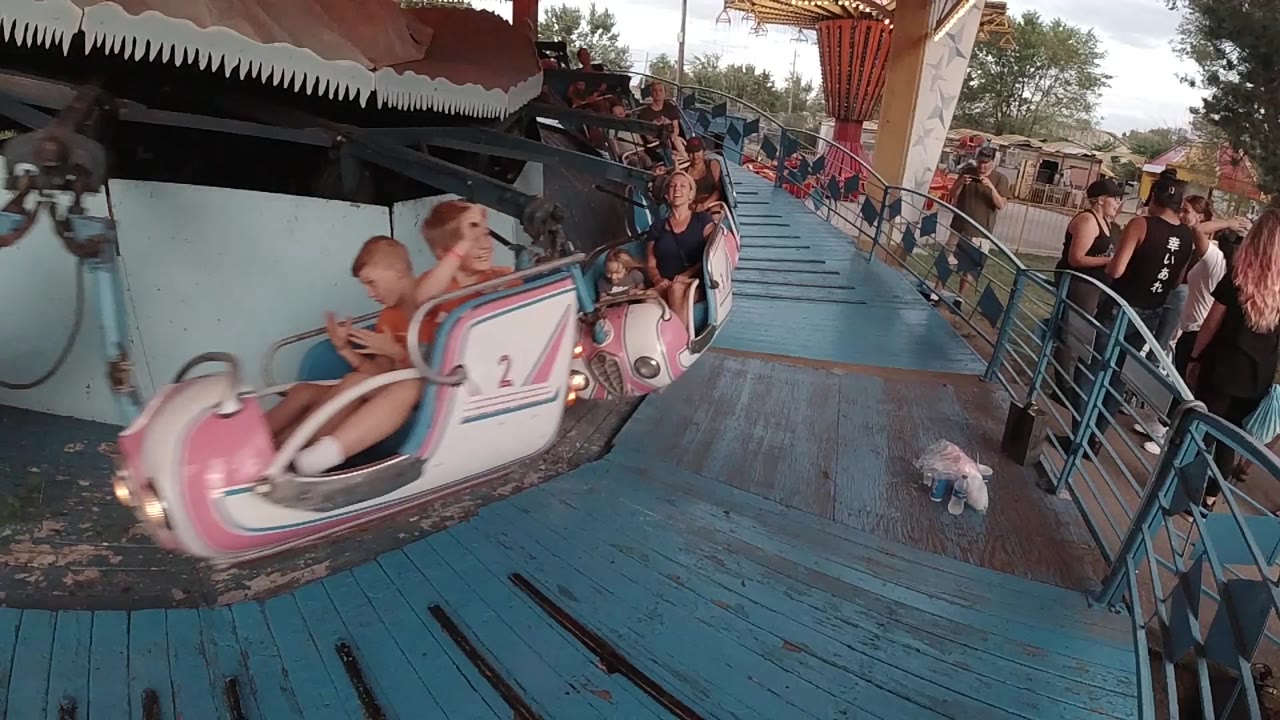 Pink airplane carousel car entering beside a blue ride platform