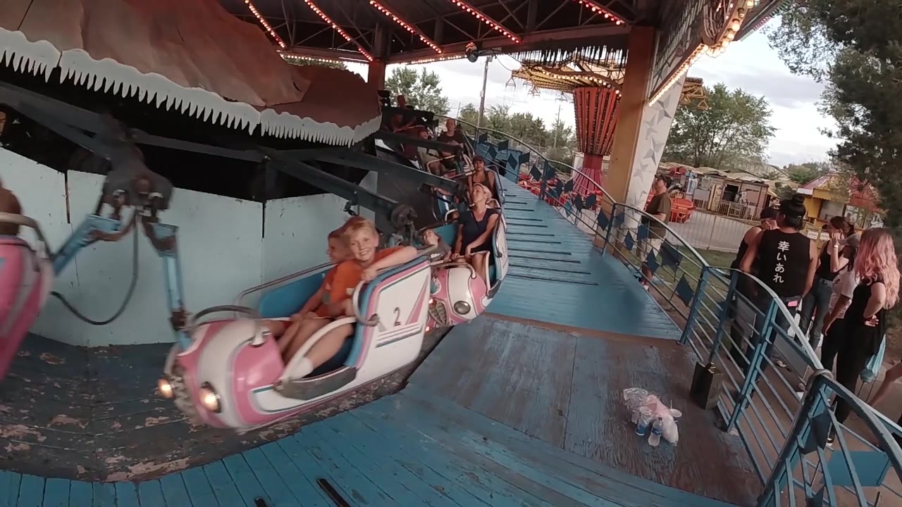 Child rides in a pink car near the platform railing.