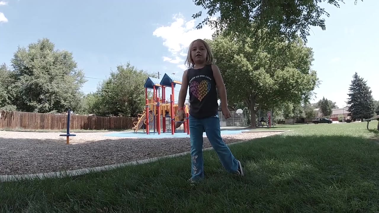 Young girl standing with one foot out on grass.