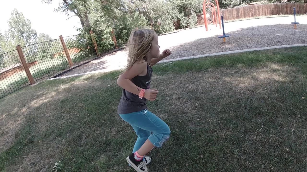 Girl mid-run with playground ahead.