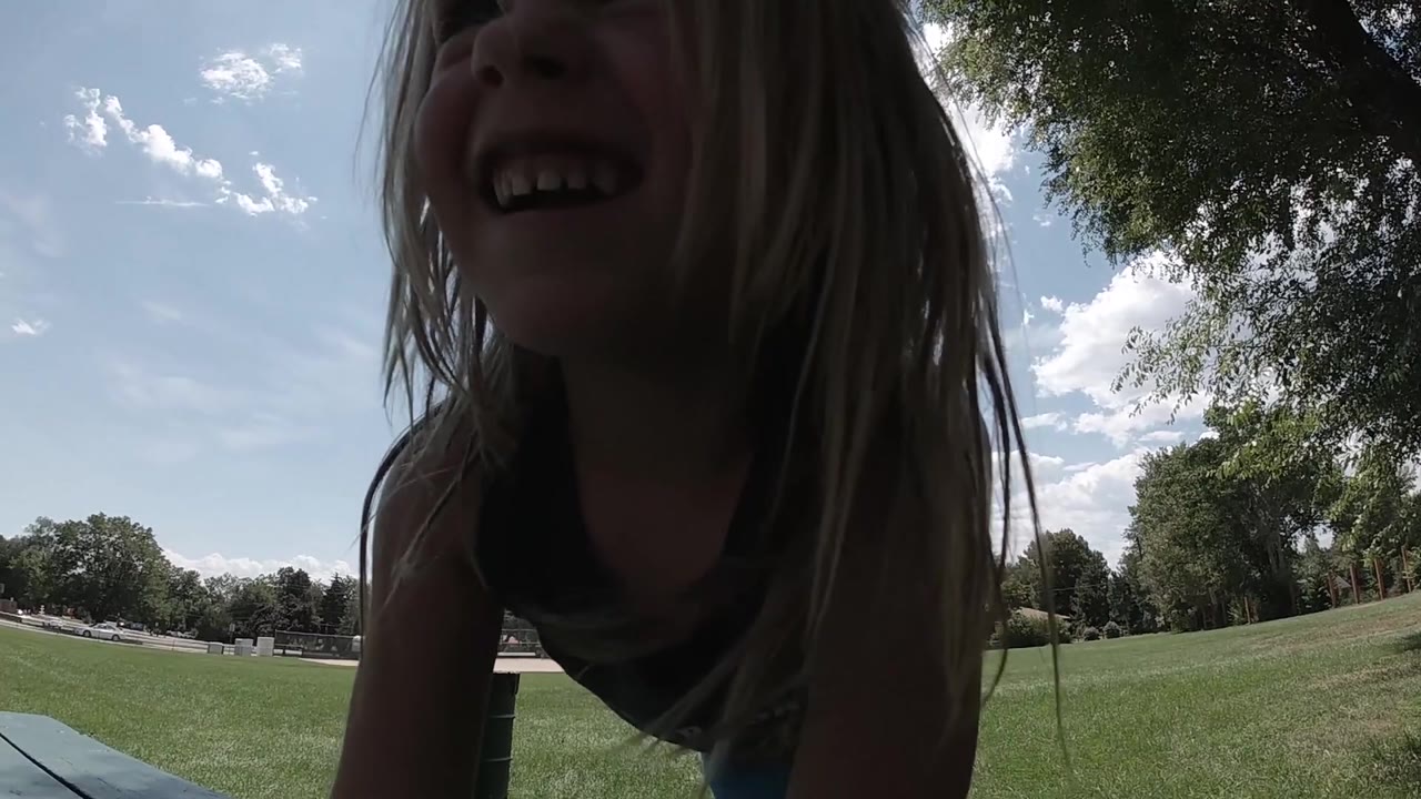 Close side view of laughing girl in a grassy park.