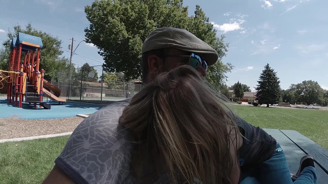 Blonde girl leans into father at picnic table.