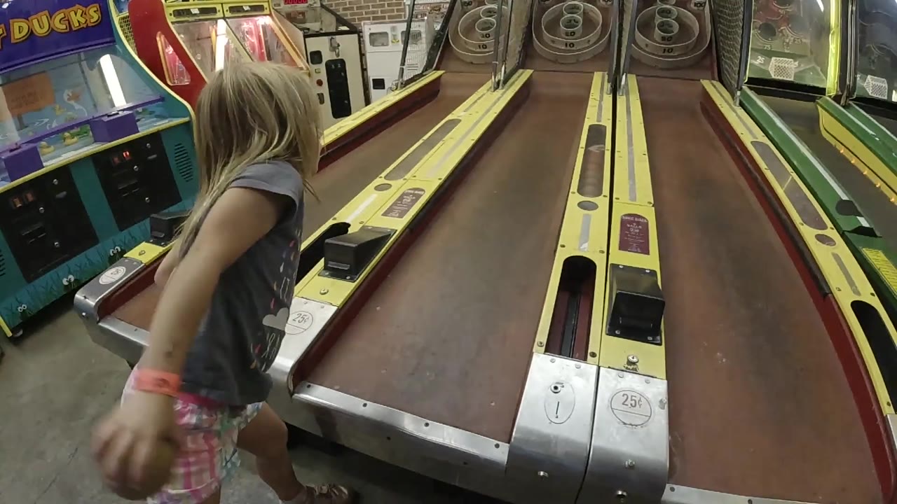 Girl extends her arm beside the skee-ball lane.