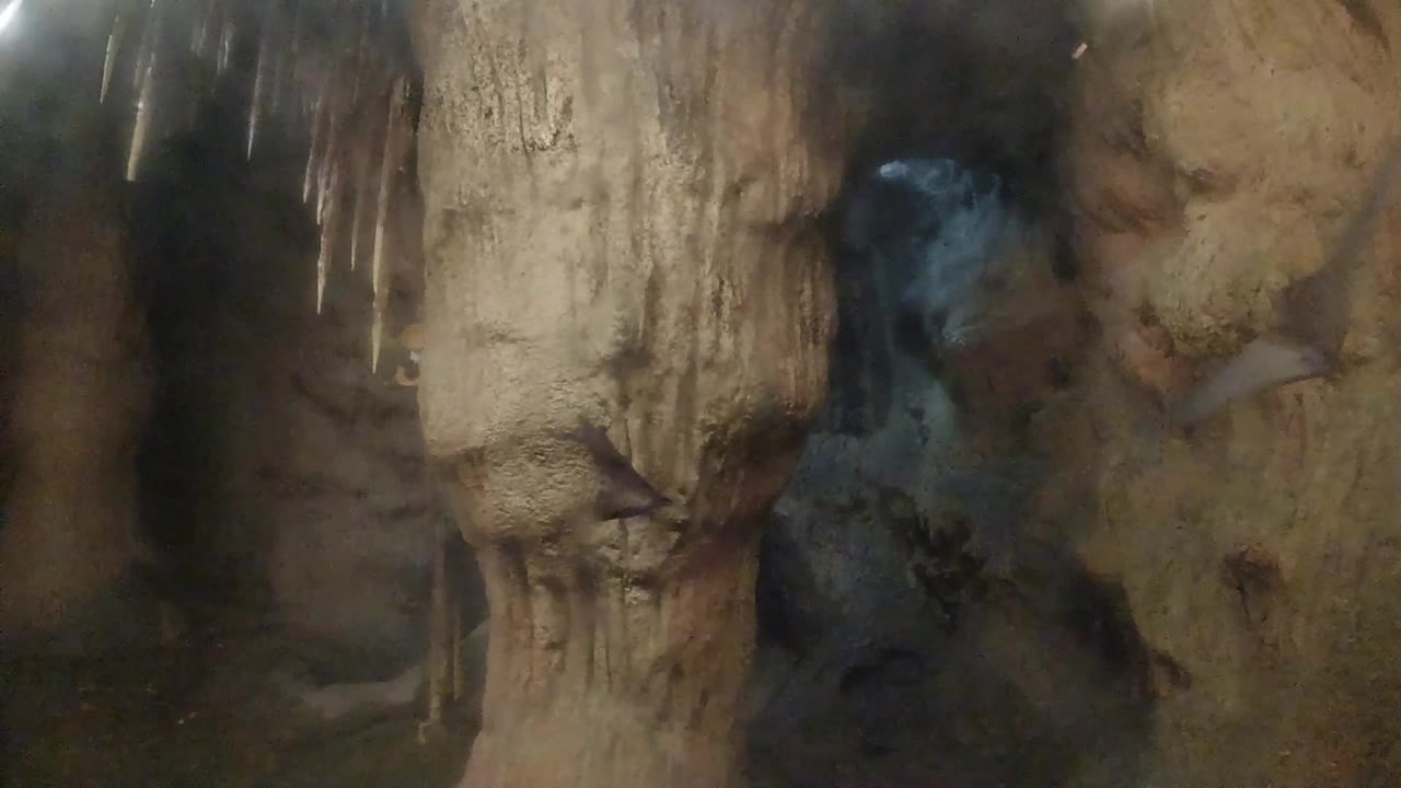 A similar early view shows the pale foreground rock slightly more centered against tan cave walls and a blue-gray recess, with no visible people.