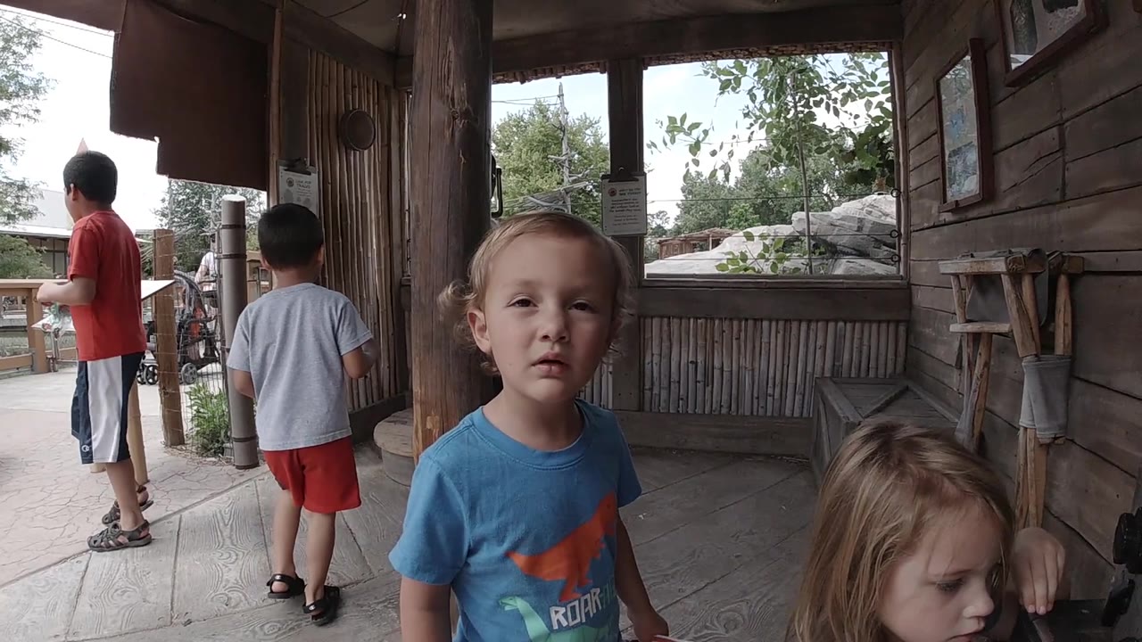 Young boy looking toward the camera under a covered wooden area.