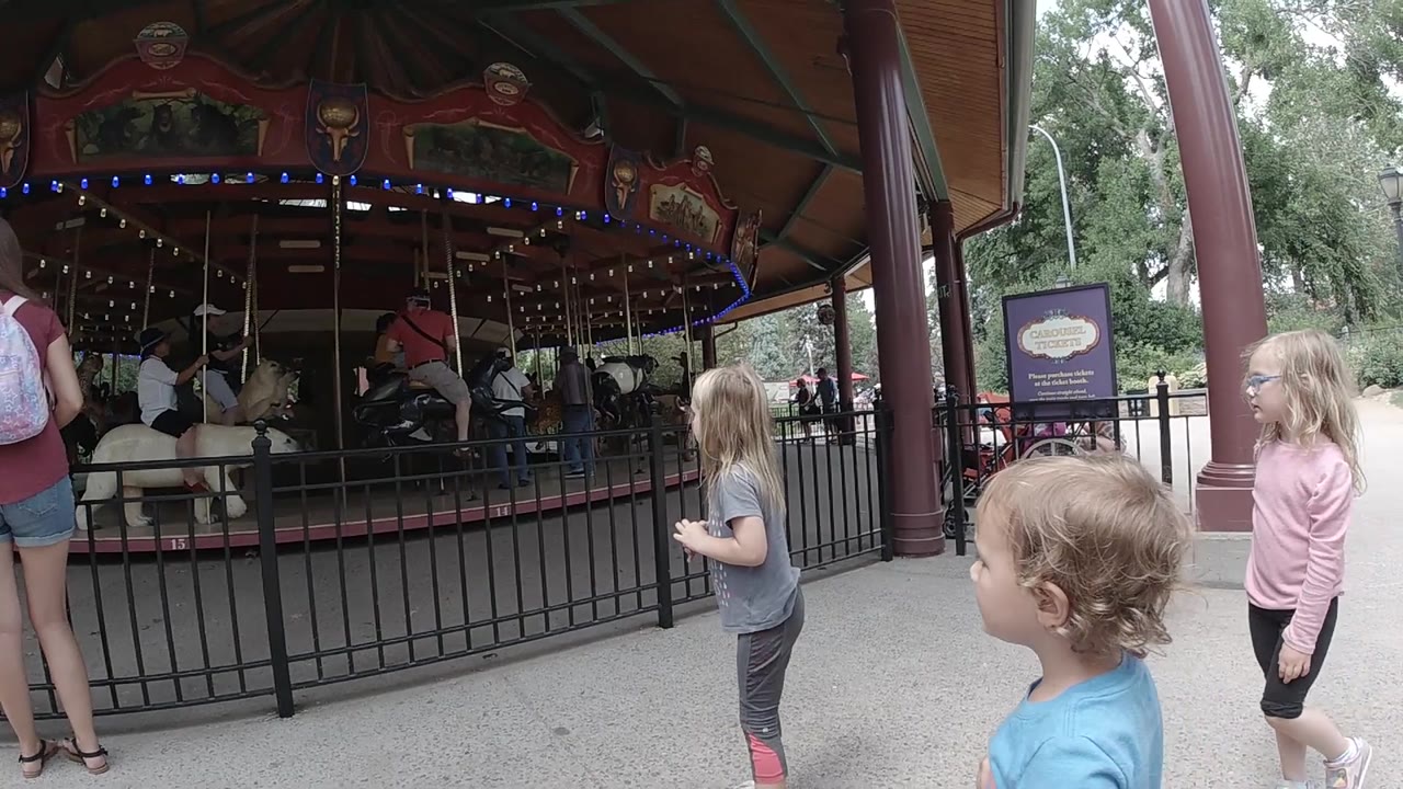 Kids walk along the carousel fence.