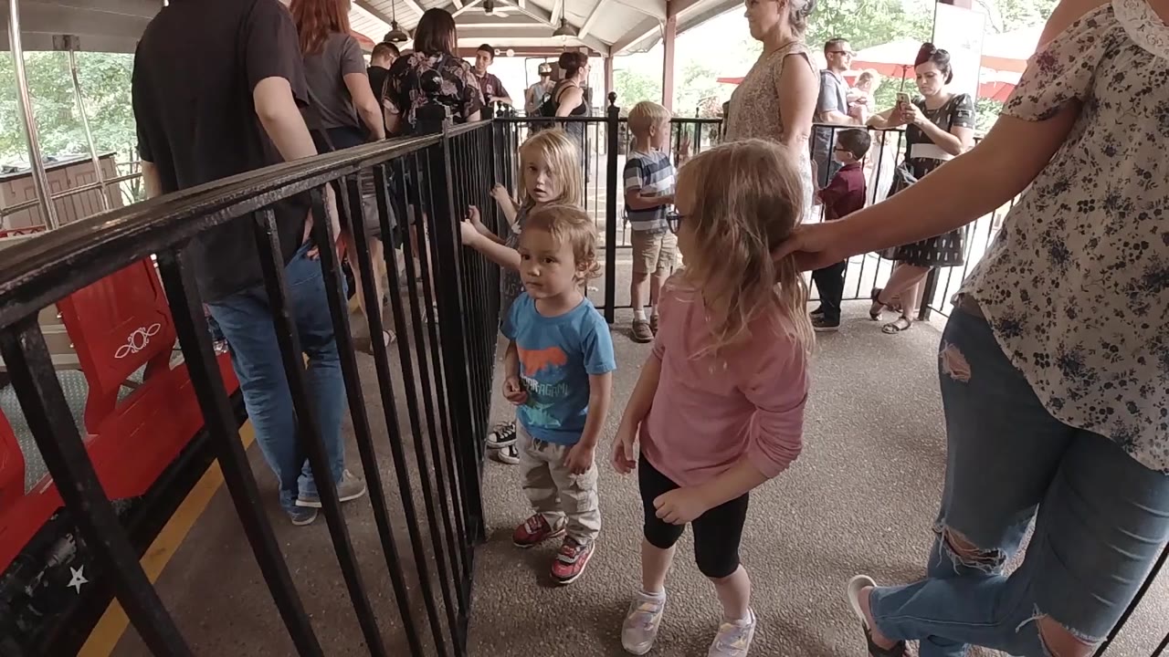 Children stand close to the railing while a guardian reaches toward them.