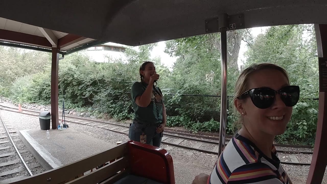 At 0:02 in Colorado, the woman in sunglasses is partly cropped at the right edge while the standing woman near the rails becomes more central under the shaded platform.