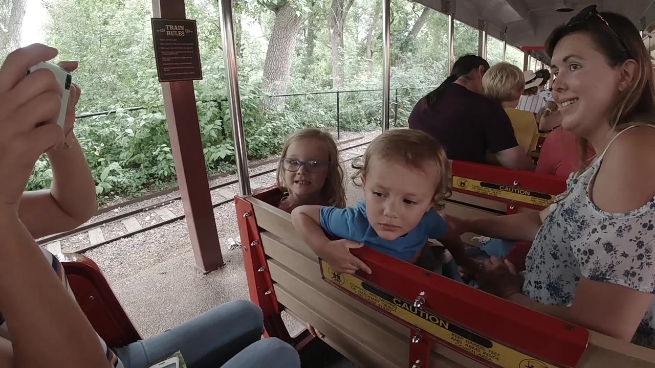 Smiling woman beside children on red and cream bench.