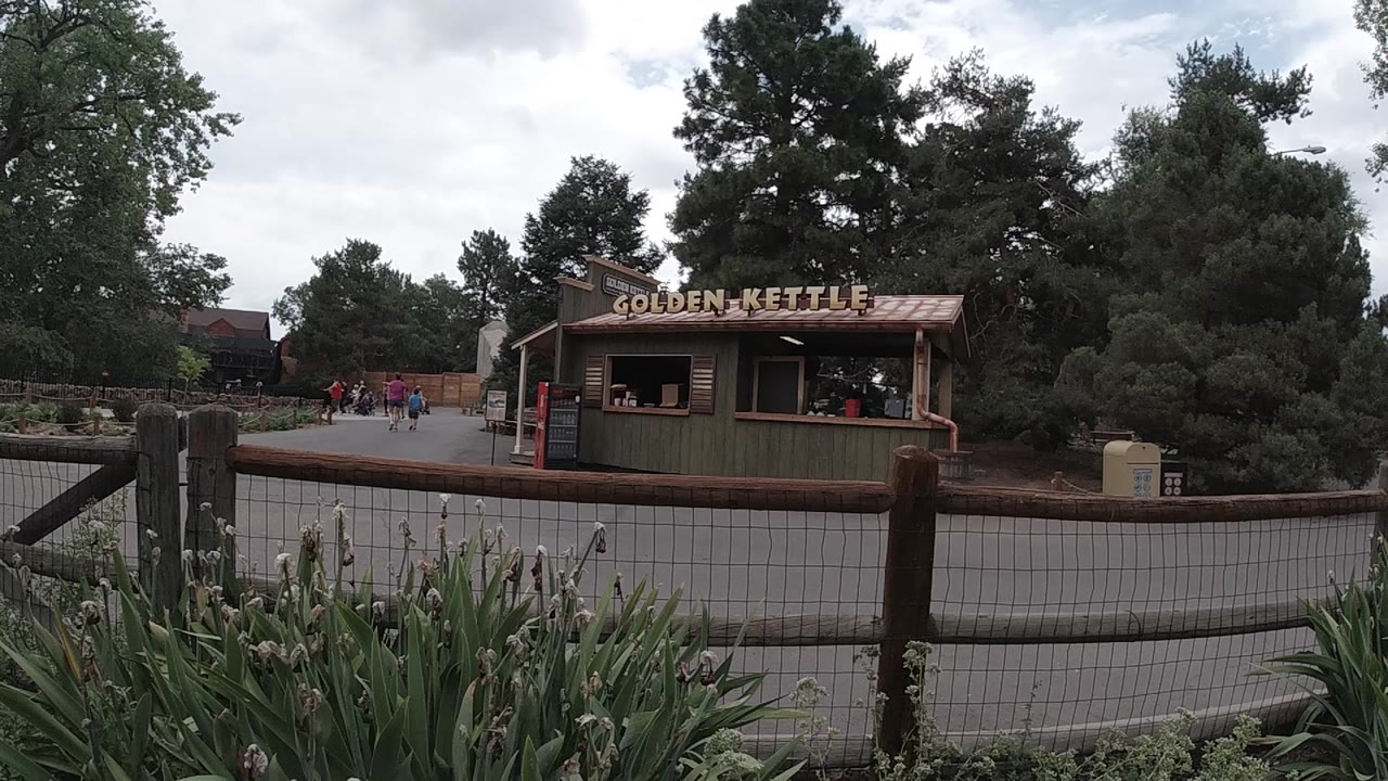 Food stand centered beyond a fence with trees around it.