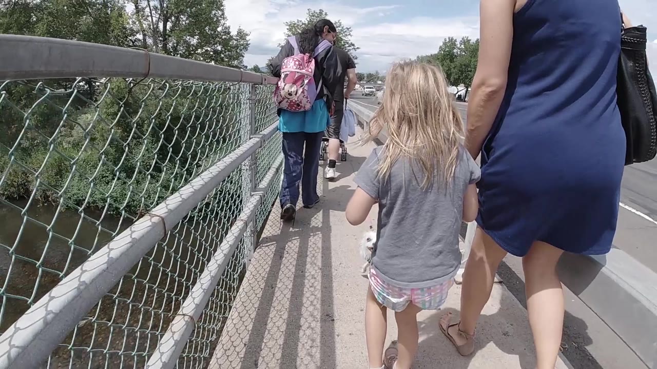 Girl and woman following pedestrians on bridge sidewalk