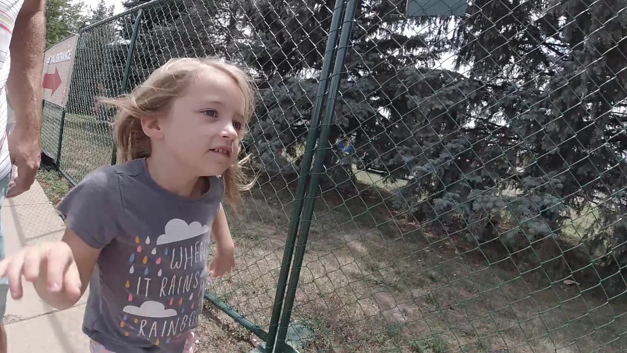 Young girl running past a chain-link fence.