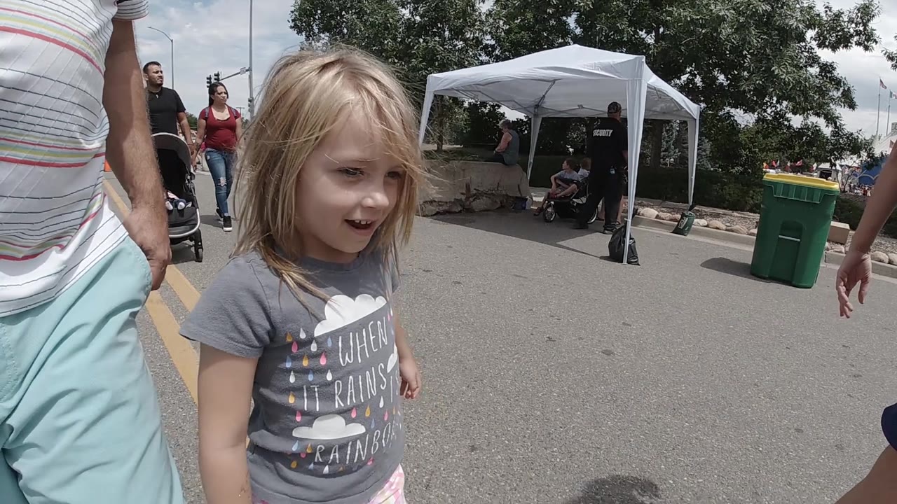 Smiling girl walks with adults along a paved street.