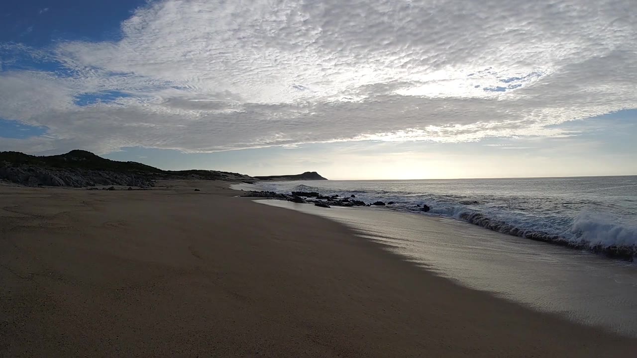 Cloudy ocean shore with distant hills