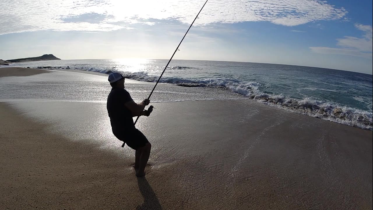 Fisherman leaning back near the surf