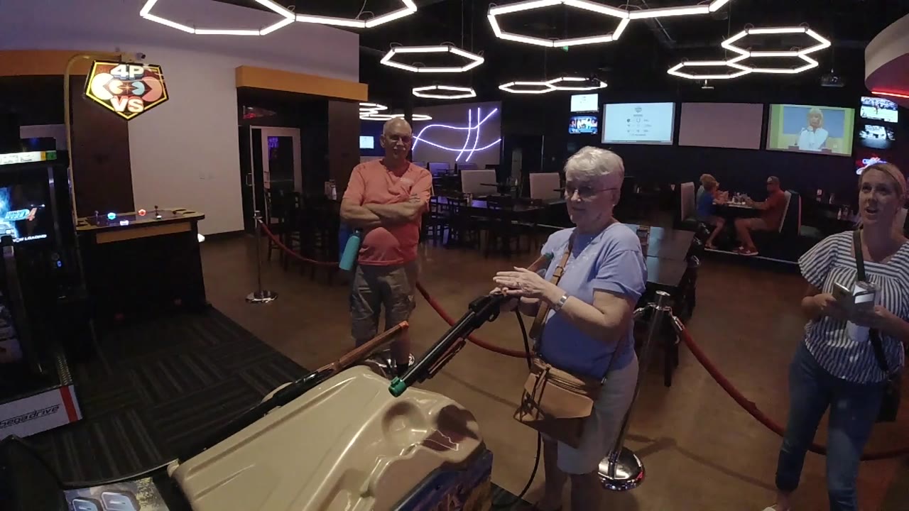 Senior woman faces the rifle game with bystanders nearby.