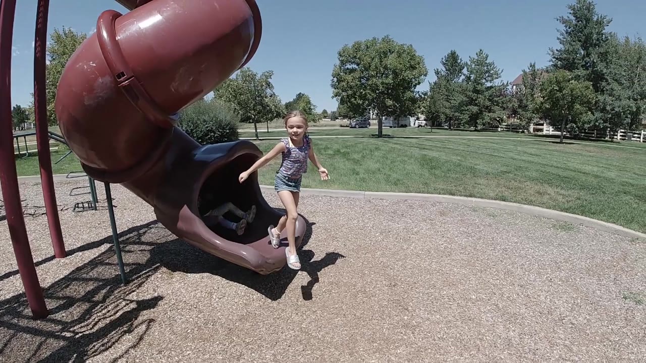 Girl steps away from the slide onto the playground surface.