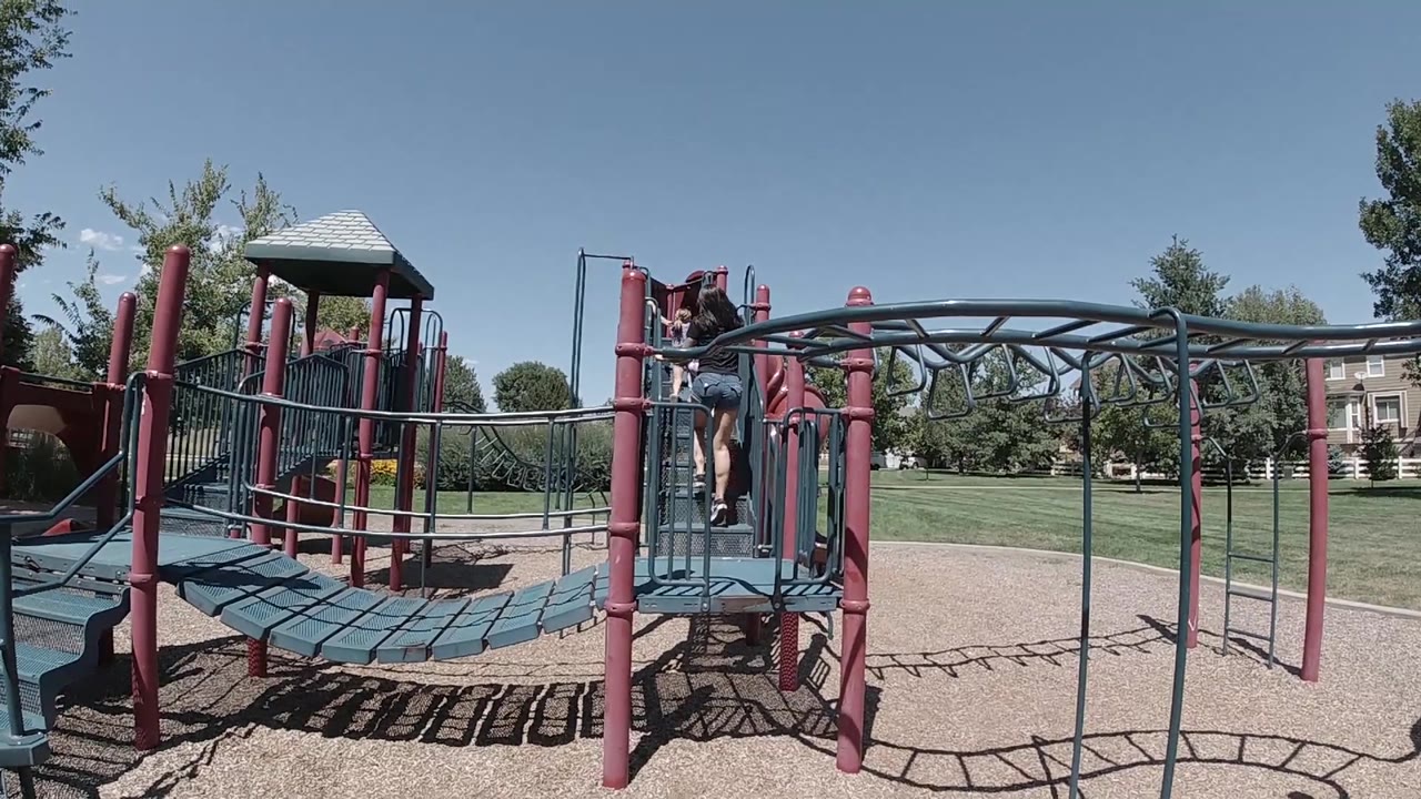 Child climbing near a playground platform with strong shadows on the ground.