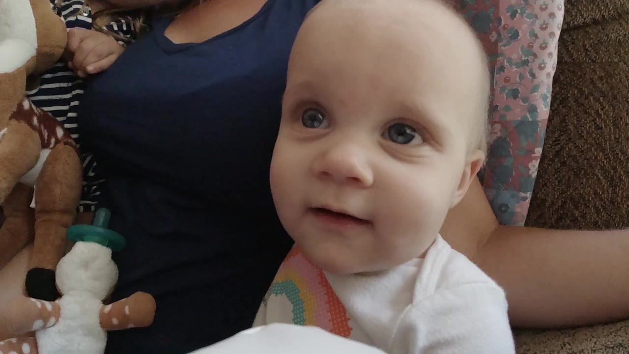 Baby on a couch looking up beside a stuffed animal
