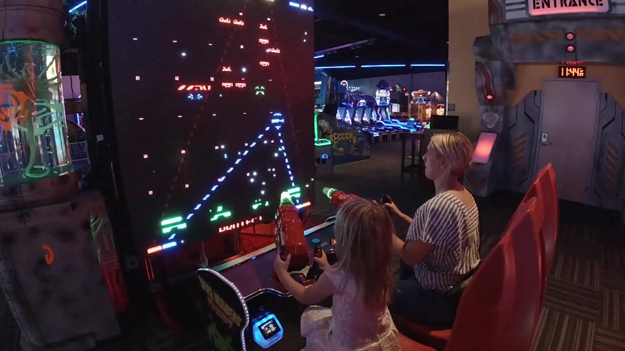 Arcade entrance sign and game cabinet beside seated players.