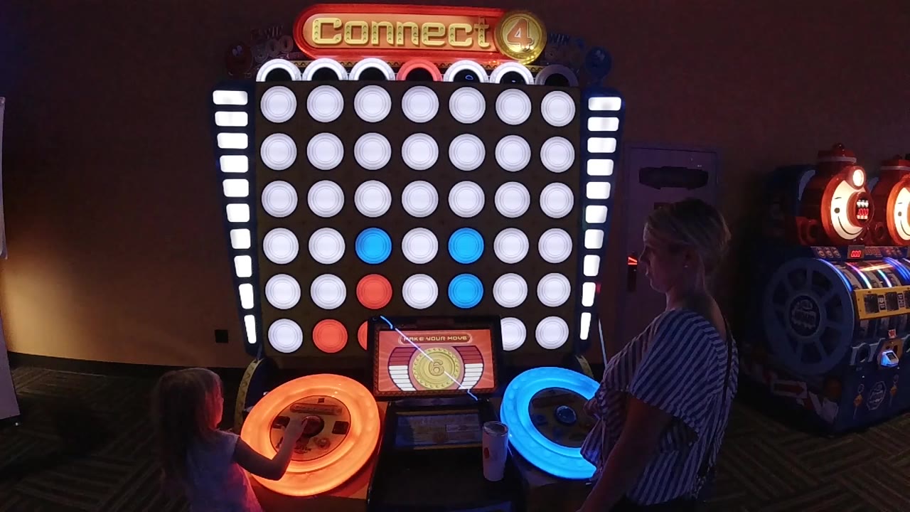 Mother and daughter at a lit Connect Hoops arcade game.