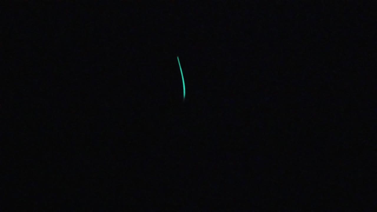 Near-black frame with small teal-green luminescent marks in the upper-center region; no visible people.