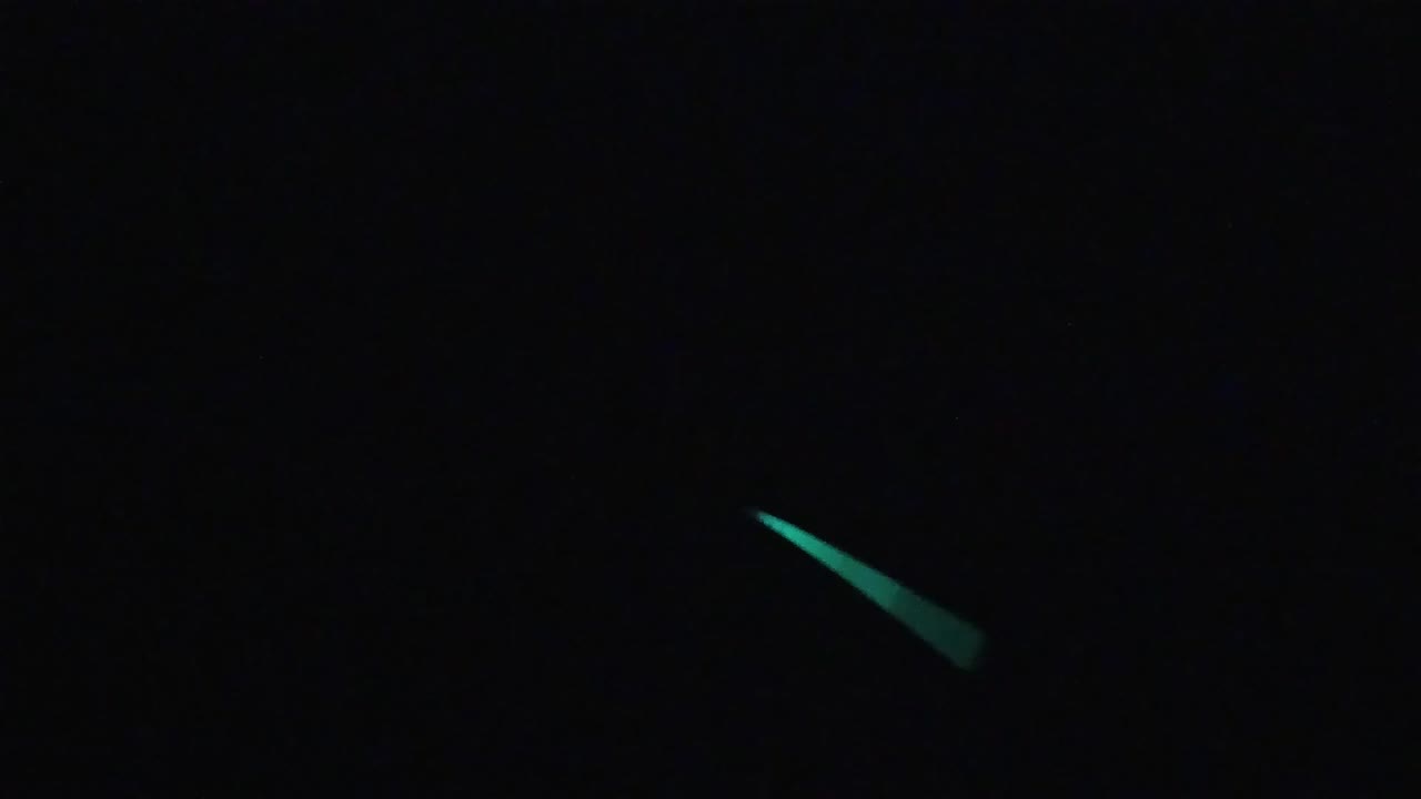 Near-black frame with teal-green luminescent marks toward the upper-right region; no visible people.