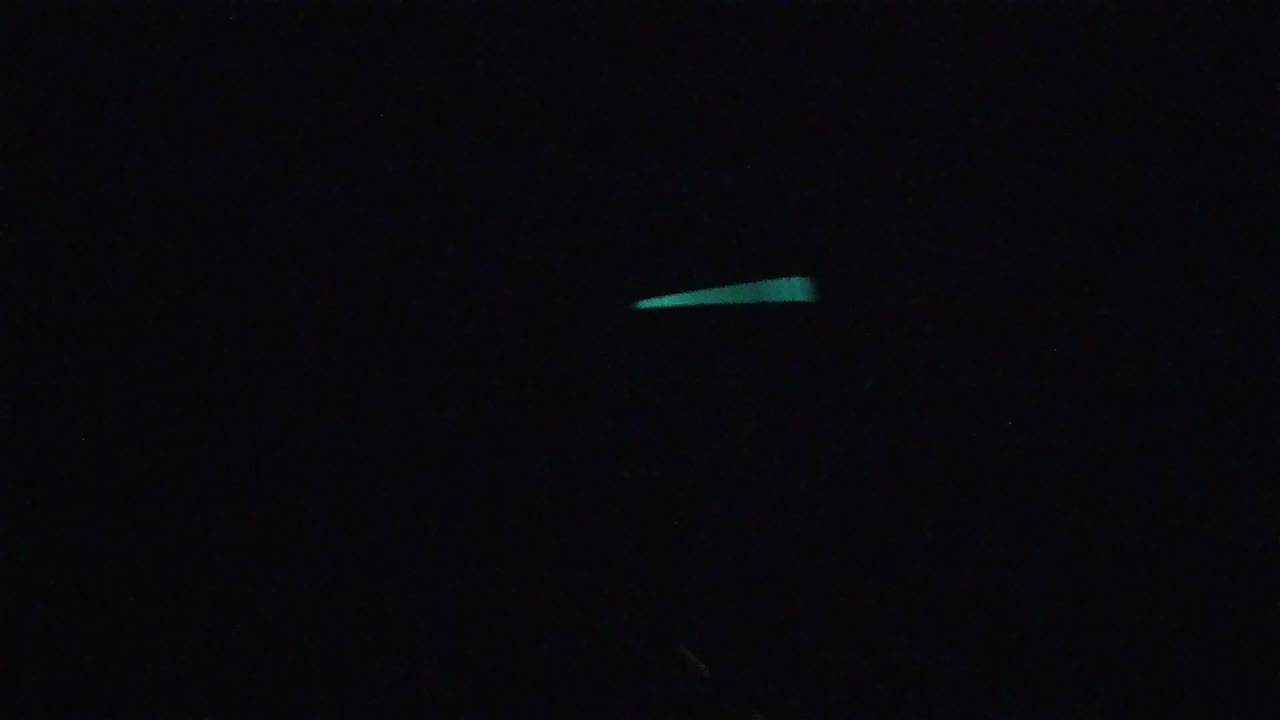 Near-black frame with scattered small teal-green diagonal light streaks; no people, buildings, or identifiable structures visible. No location identifiable.