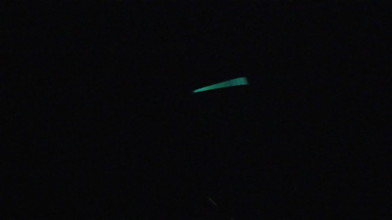 Near-black field with scattered teal-green diagonal light marks; no people or identifiable structures visible. No location identifiable.