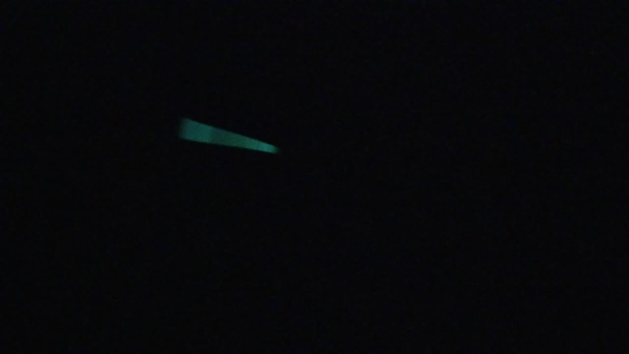Early frame showing short green light-stick traces separated by large areas of black, with no visible people.