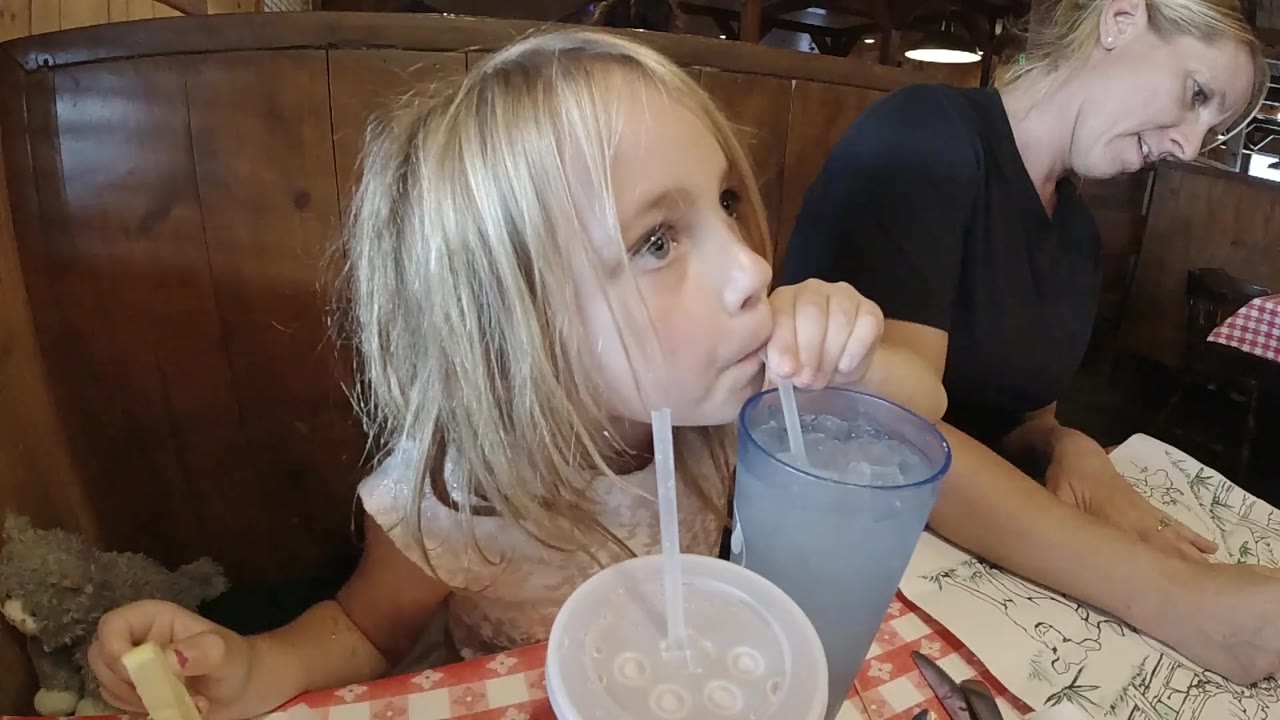 Girl holds a straw near her mouth at a booth