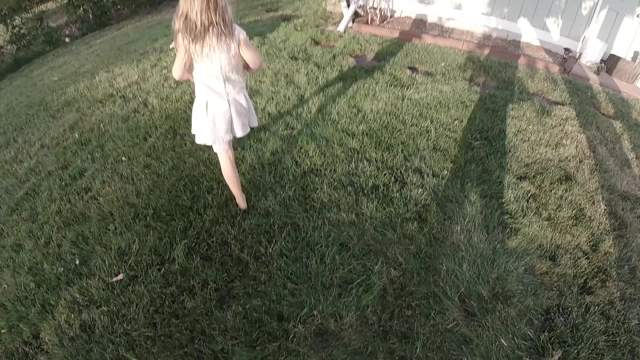 Girl walking away on grass with shadows beside her.