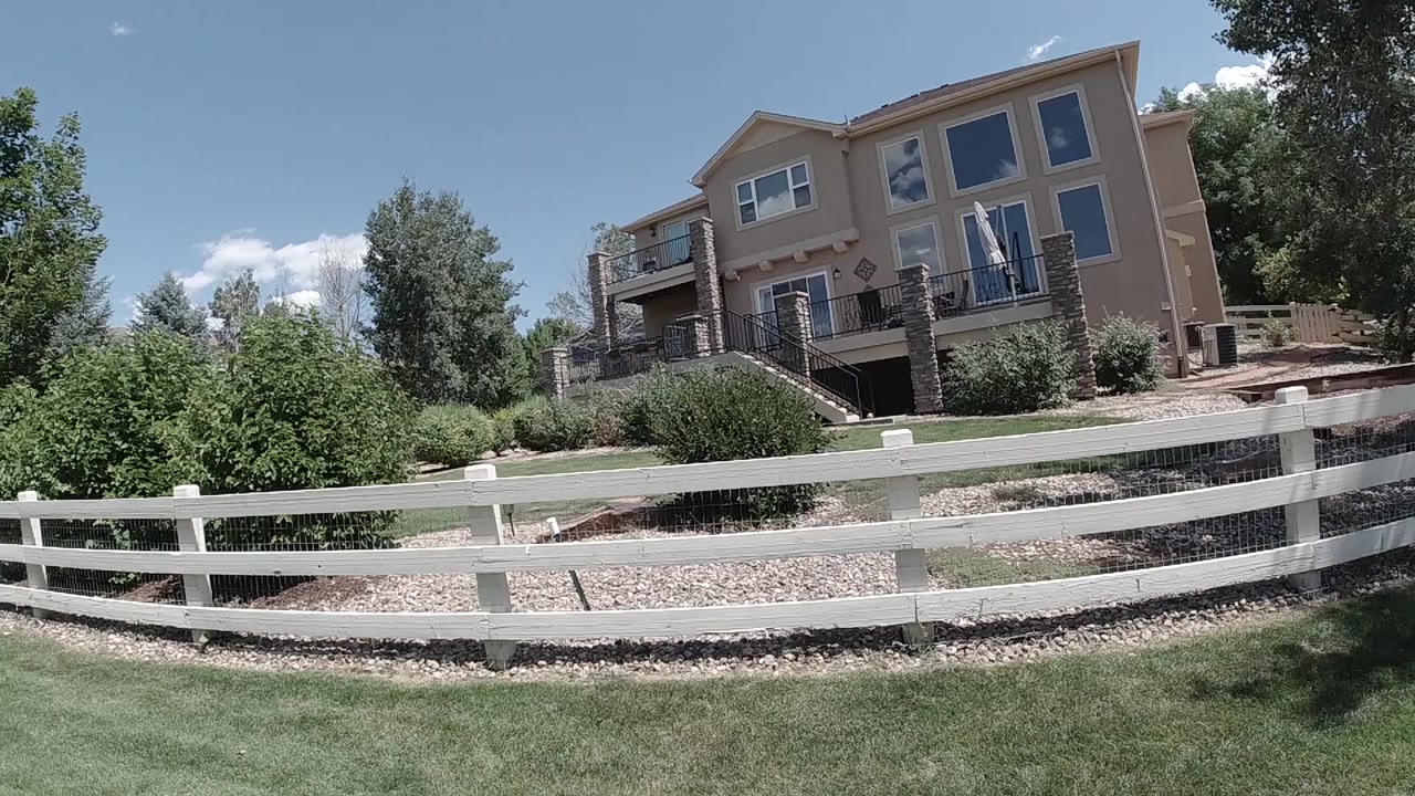 Tan house behind a white fence and green lawn