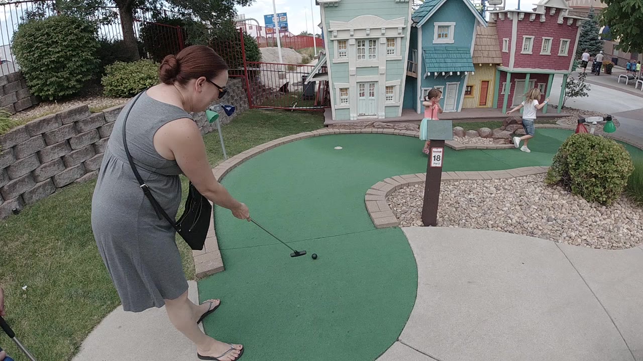 Woman prepares to putt on a miniature golf green.