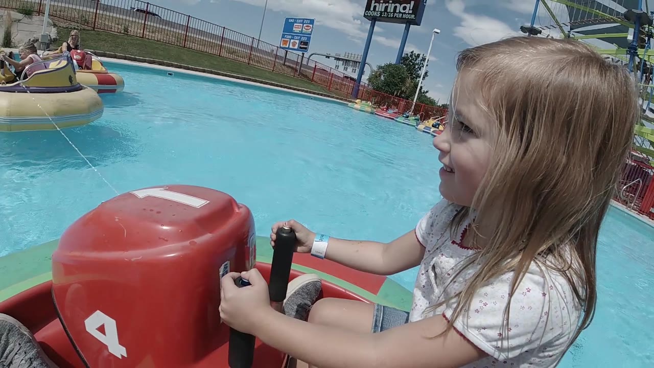 Girl steers with other bumper boats across the pool.