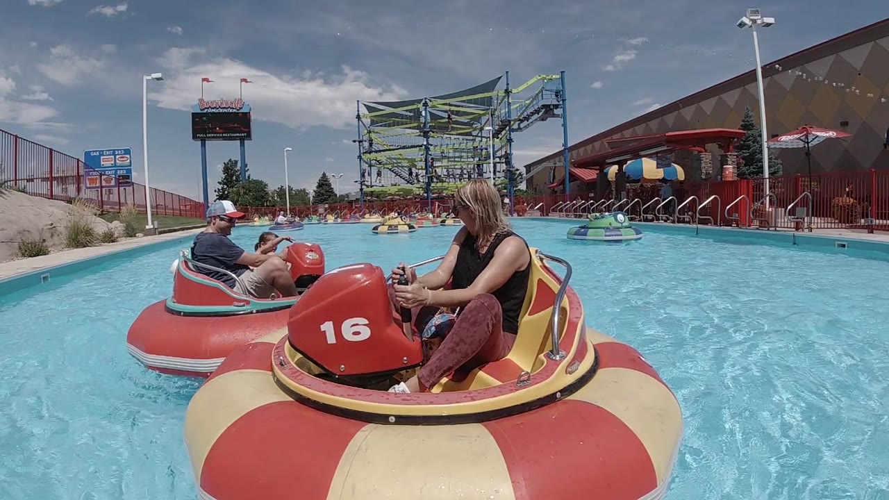 Woman steering a bumper-style water boat in a bright pool