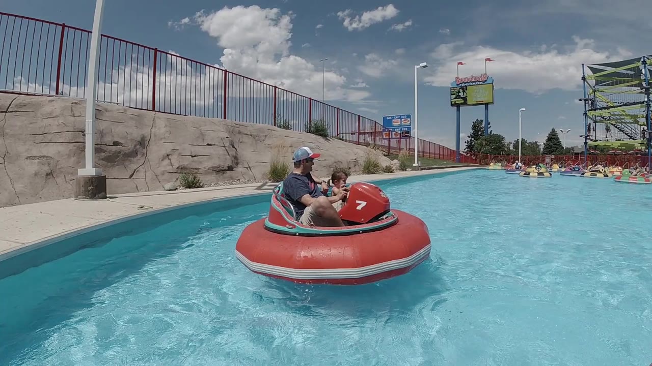 Red bumper boat with adult and child in a blue pool