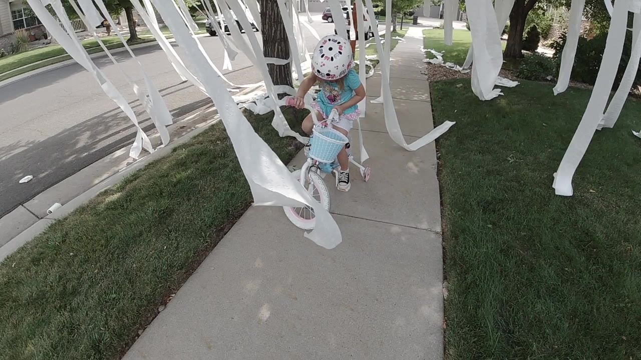 Girl on a small bicycle under white streamers